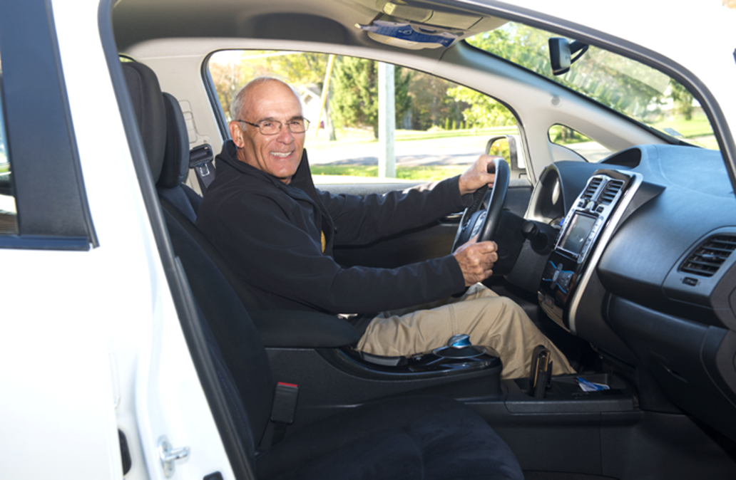 Older man sitting in car, smiling